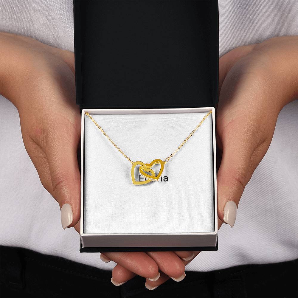 Gold interlocking hearts necklace in a gift box, held